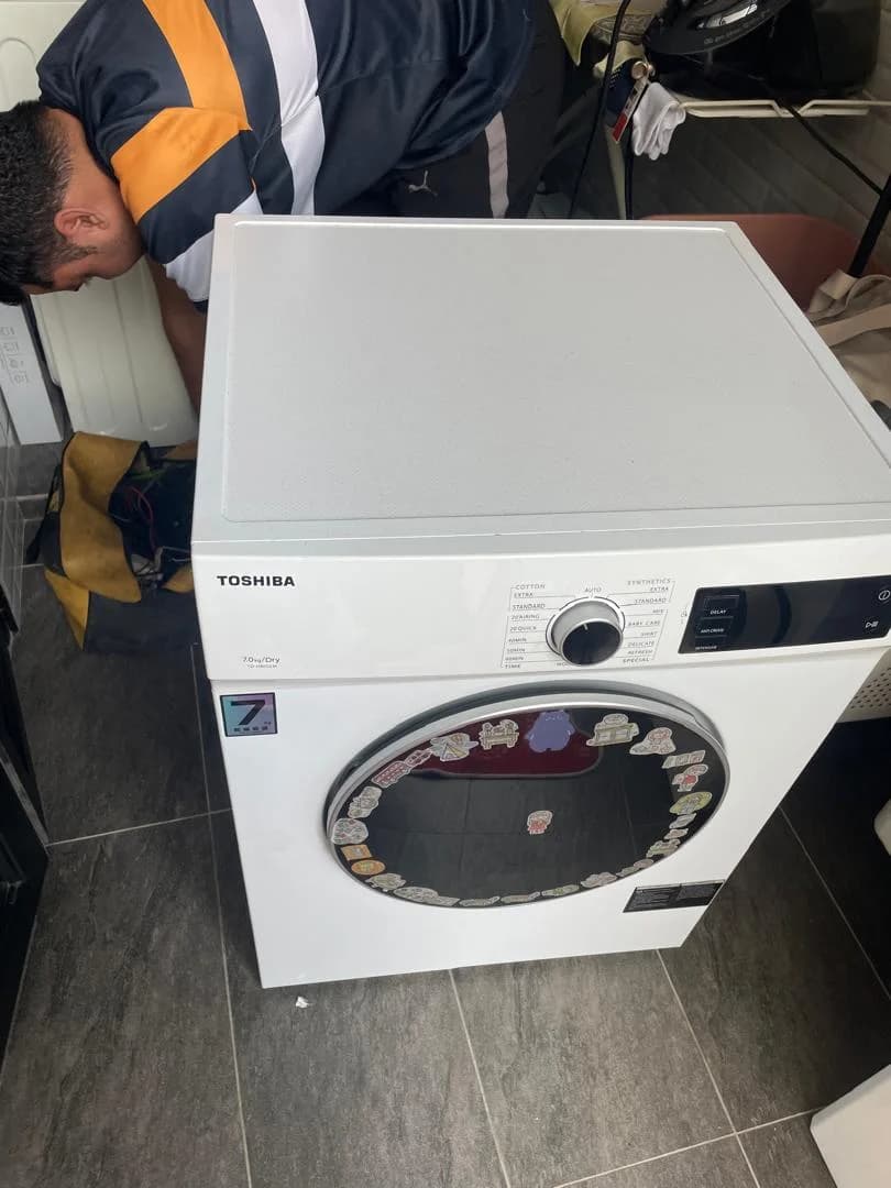 Technician inspecting a white Toshiba tumble dryer