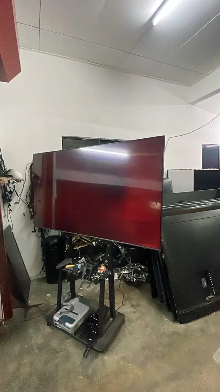 Television mounted on a service stand beside workshop equipment