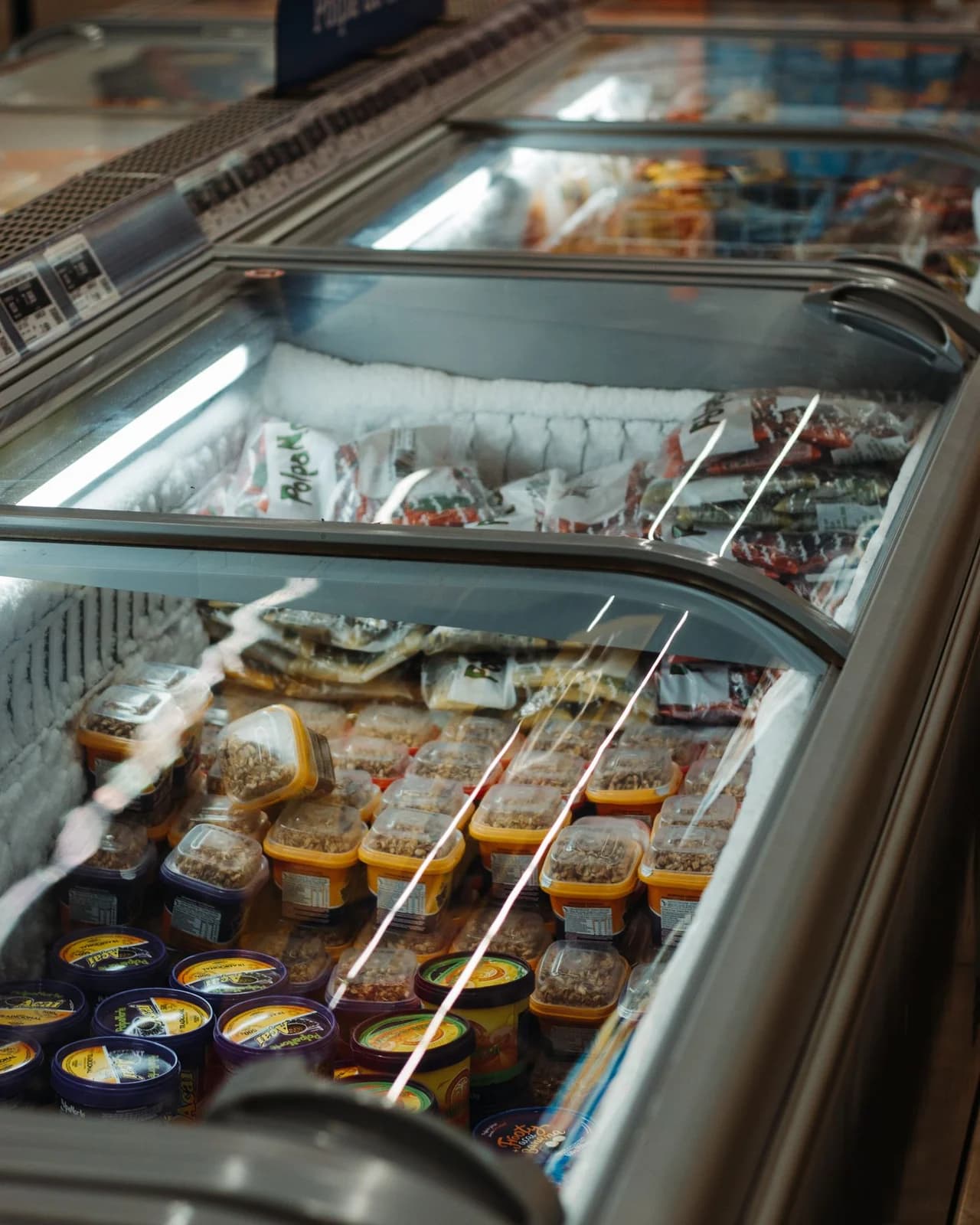 Glass-top commercial freezers displaying frozen food